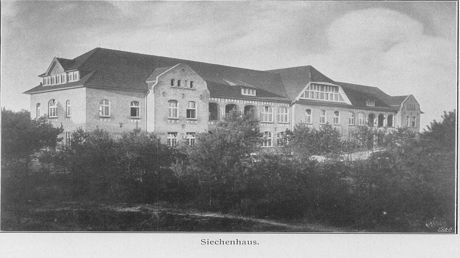 Schwarz-Weiß-Foto: großes dreistöckiges Haus mit vielen Bäumen im Vordergrund